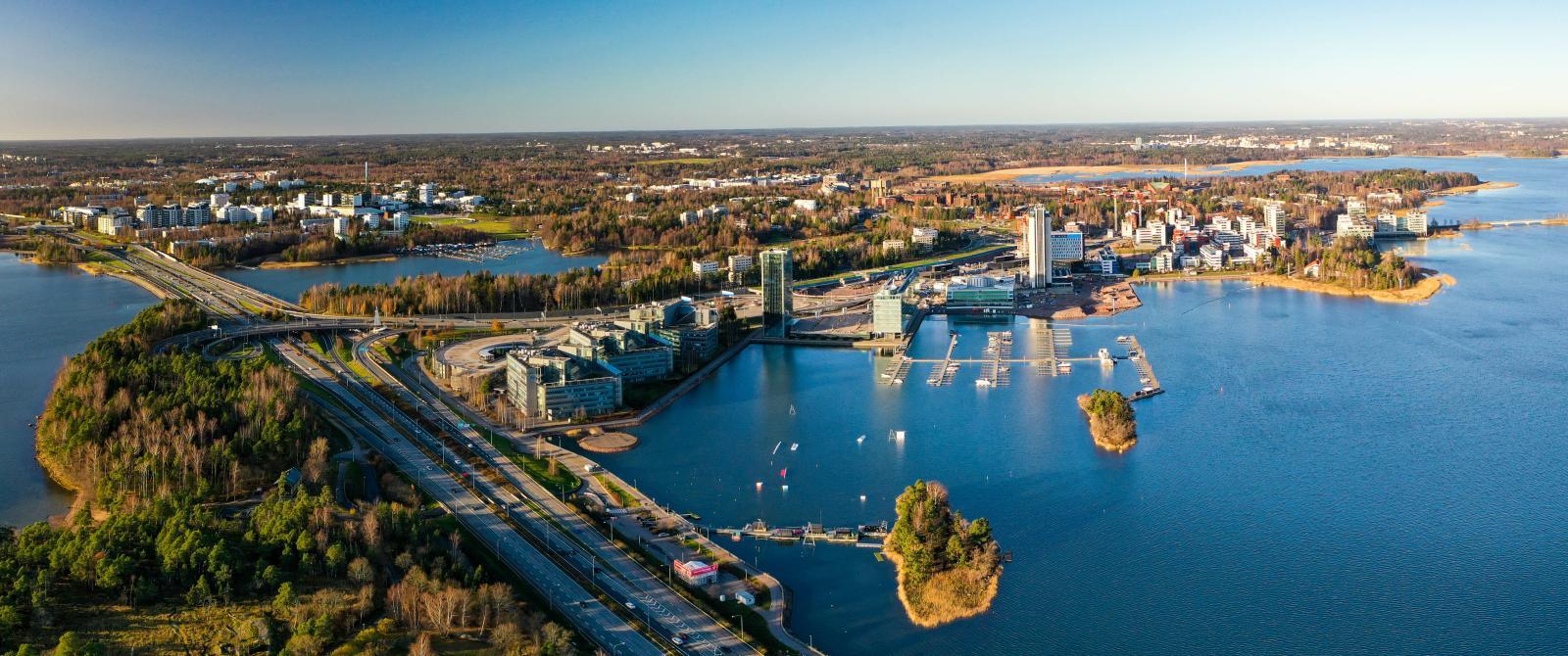 Luftaufnahme von Espoo, eine moderne Stadt mit kleinem Hafen umgeben und durchzogen von vielen Bäumen.